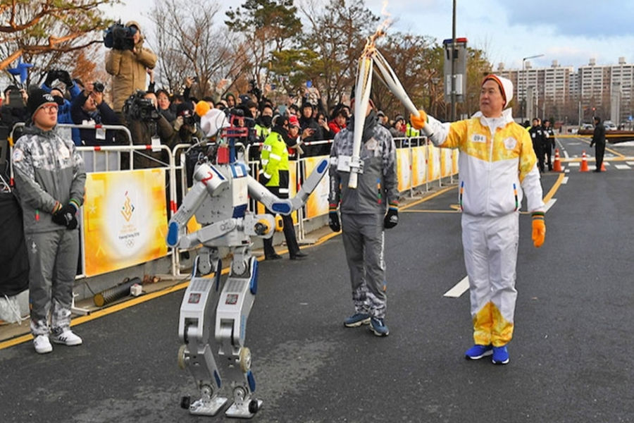 A Japanese runner passing the torch over to a Robot. Olympics 2020 Japan